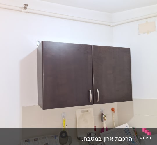 ארון מטבח כהה עם ידיות מתכת, כיור וברז
